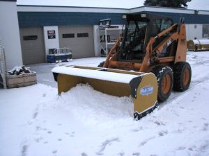 snow pusher attached to skid steer pushing snow