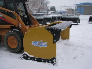 HLA snow pusher mounted on skid steer pushing snow