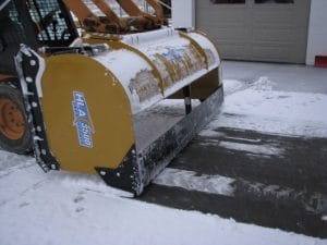 HLA snow pusher mounted on skid steer using back drag feature