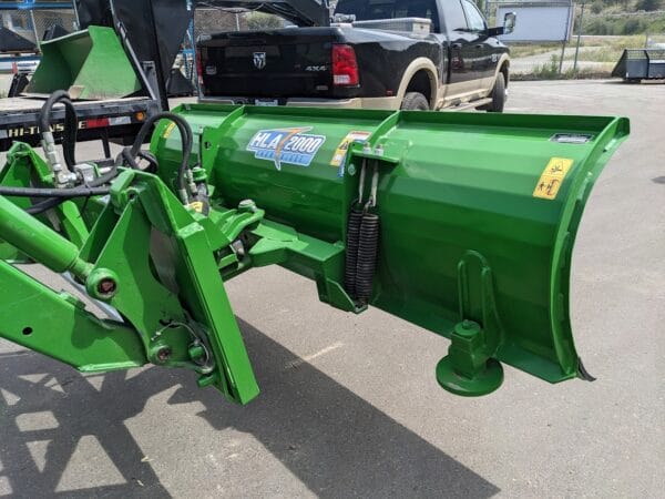 HLA 2000 on JD Tractor HLA 2000 series 90" snow blade with JD440/540 quick attach mounted on JD tractor side view