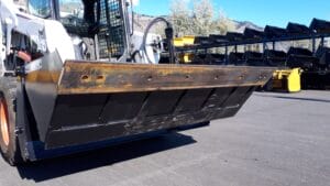 Skid Steer 4 in 1 Bucket in open position mounted on Bobcat showing bolt on cutting edge