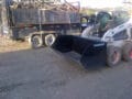 dumpster bucket on bobcat skid steer beside